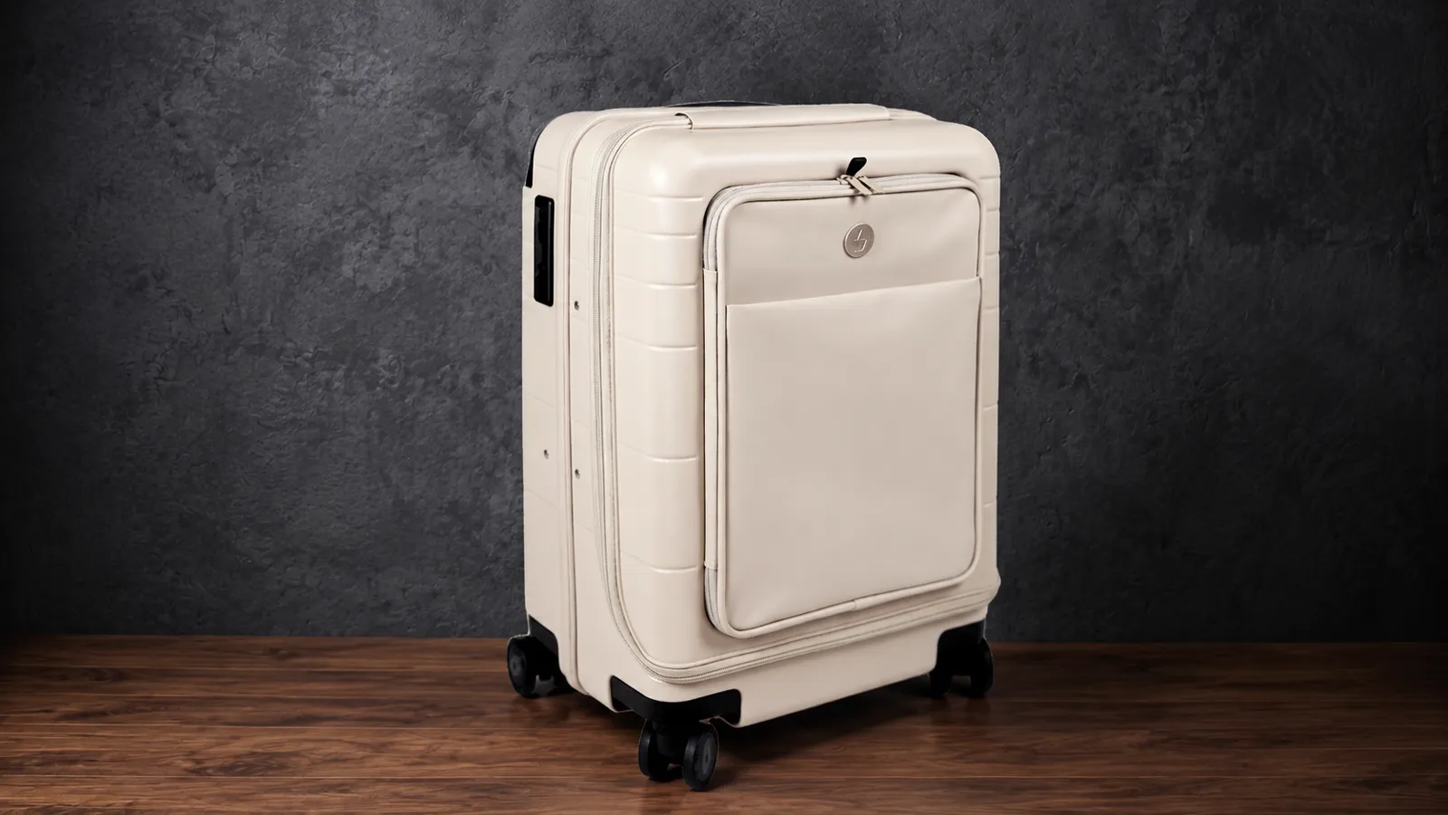 The Vasy carry-on in oat cream, three-quarter view in the dark studio.